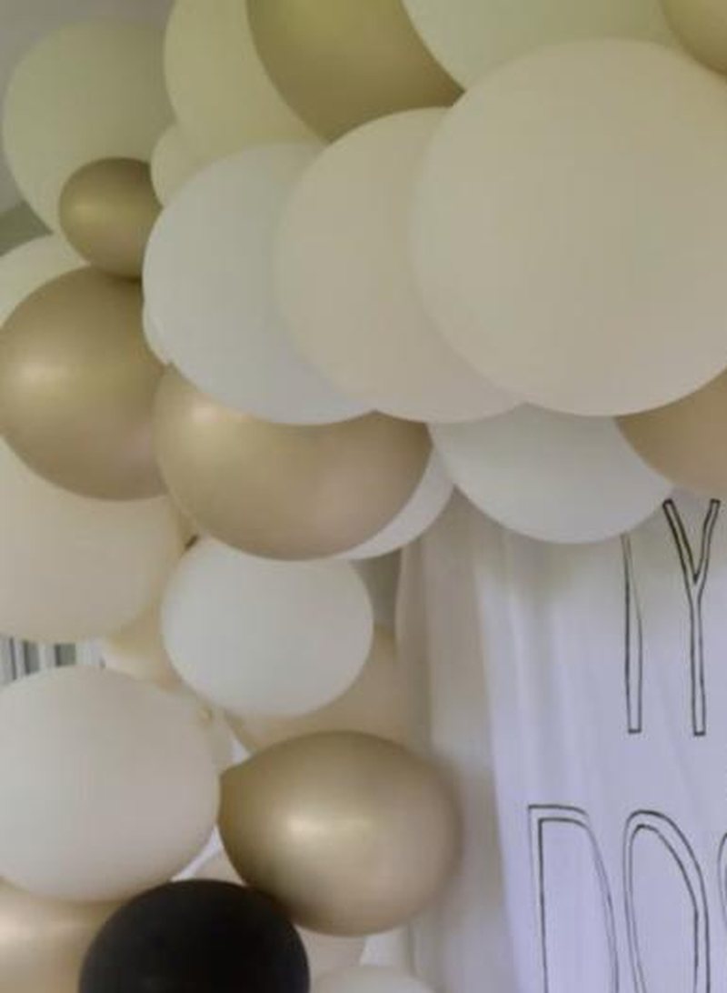 Champagne and black organic balloon garland over a party backdrop