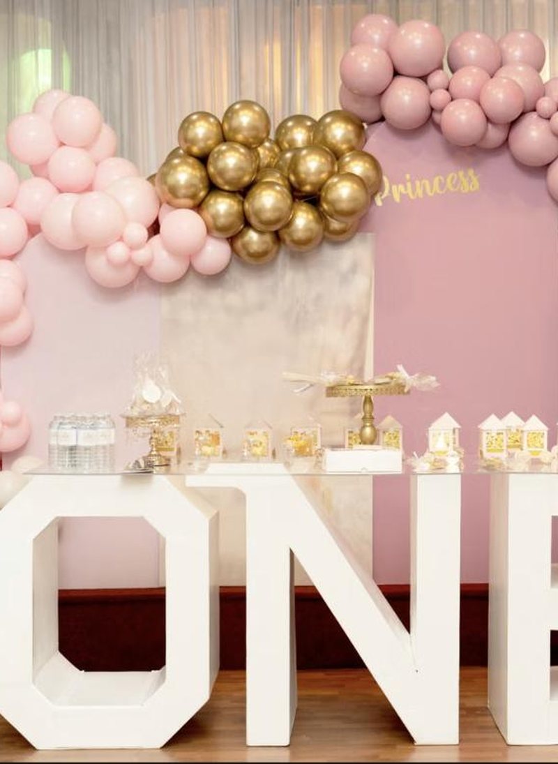 Full venue set for a first birthday with balloon garlands and giant ONE letters